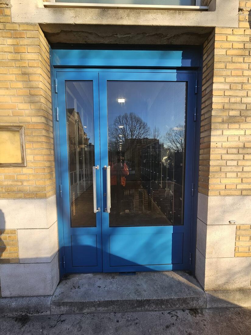 Porte double vitrée bleue sur façade en brique